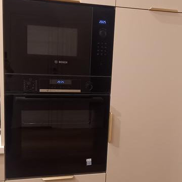 Horno pirolítico Bosch negro empotrado junto a anafe Samsung acero inoxidable