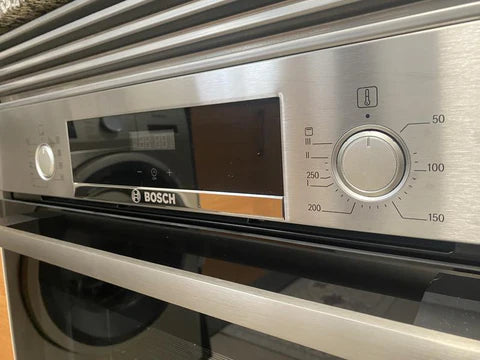 Primer plano de los mandos de control y pantalla digital del horno Bosch HBA512BR0, destacando la función de programación electrónica.