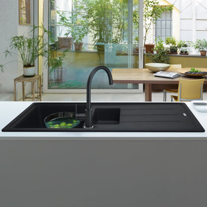 El grifo de cocina Franke Mythos Masterpiece 115.0711.554 antracita integrado en un ambiente de cocina de estilo industrial, con paredes de ladrillo visto, estanterías metálicas y electrodomésticos de acero inoxidable.